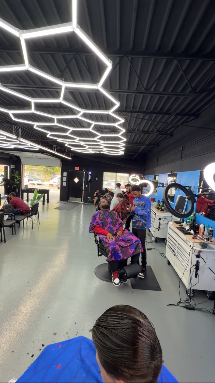 Barbers and clients inside Limited with blue workstations and geometric ceiling lights